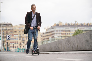 Businessman on daily commute riding micro scooter