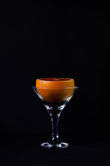 Grapefruit in a martini glass on a black background.