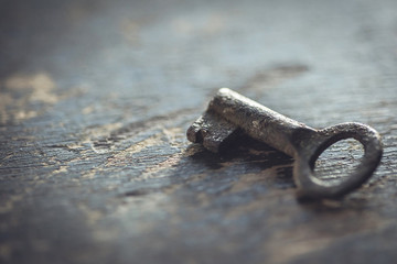 Shallow DOF. Vintage worn out key on a wooden background.
