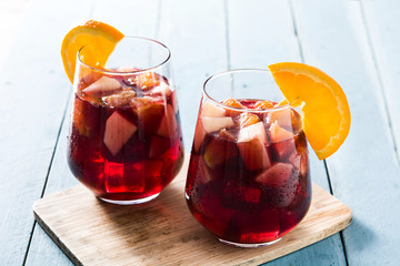 Red wine sangria in glass on blue wooden table. 