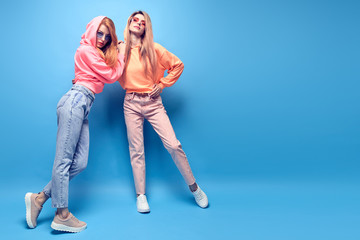 Two Young hipster Woman in Stylish neon hoodie, fashion jeans having fun. Funny adorable...