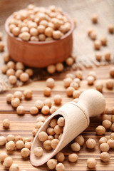 Chickpeas in bowl and scoop on brown wooden table