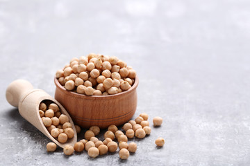 Chickpeas in bowl and scoop on grey wooden table