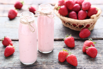 Smoothie in glass bottles with strawberries on grey wooden table
