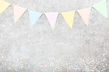 Colorful confetti and paper flags on grey background