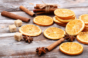 Dried orange fruits with cinnamon, star anise and sugar cubes on brown wooden table