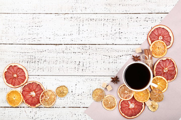 Dried citrus fruits with spices and cup of coffee on white wooden table