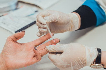 Obraz na płótnie Canvas A doctor in medical laboratory taking a blood test with a pipette. Hands closeup. Concept of a checkup for viruses, cancer and HIV infection test