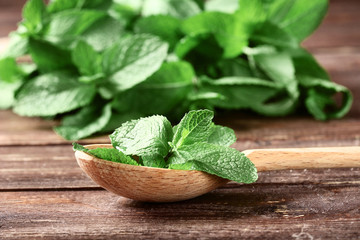 Mint leafs with spoon on brown wooden table