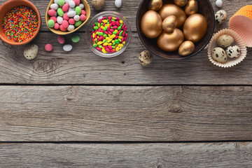 Golden eggs and candies on wooden background