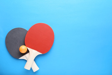 Table tennis rackets with ball on blue background