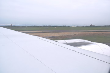 Fototapeta na wymiar plane wing while take off from runway through window frame
