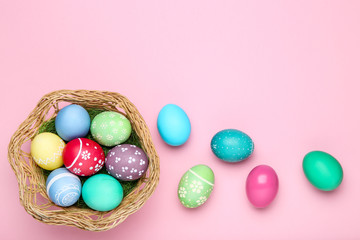 Colorful easter eggs in basket on pink background