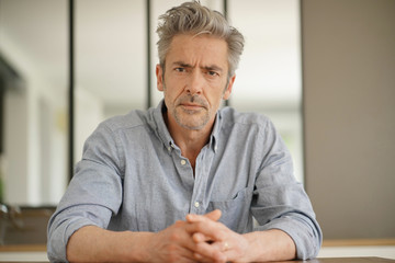 Portrait of handsome mature man looking at camera in contemporary home