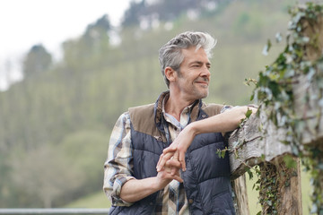 Attractive farmer smiling leaning on fence