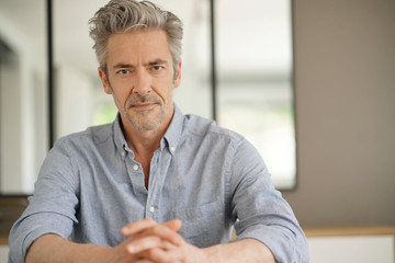 Portrait of handsome mature man looking at camera in contemporary home