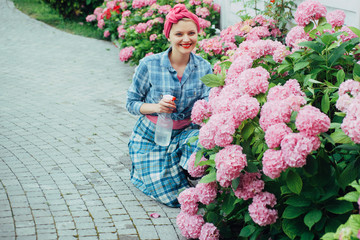 Fototapeta premium woman care of flowers in garden. Flower care and watering. soils and fertilizers. Greenhouse flowers. happy woman gardener with flowers. hydrangea. Spring and summer. Living a green life