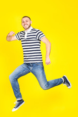 Fototapeta na wymiar Jumping young man on yellow background