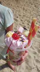 Beautiful appetizing ice cream in the hand against the sand on the beach in the summer
