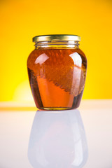Sweet honey in the comb, glass jar on wooden background