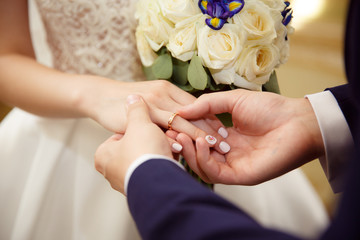 Bride and groom exchange rings at the wedding. Lovers put each other rings on the fingers.