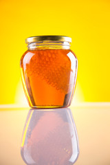 Sweet honey in the comb, glass jar on wooden background