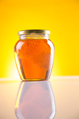 Sweet honey in the comb, glass jar on wooden background