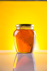 Sweet honey in the comb, glass jar on wooden background