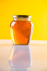 Sweet honey in the comb, glass jar on wooden background