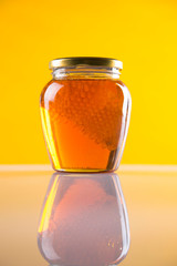 Sweet honey in the comb, glass jar on wooden background