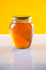 Sweet honey in the comb, glass jar on wooden background