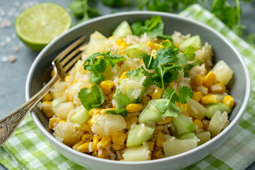 Healthy vegetarian salad with brown rice, corn, cucumber, pineapple and coriander.