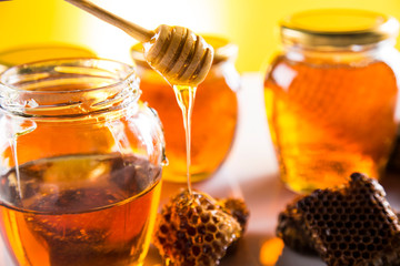 Honey in jar with honey dipper on wooden background