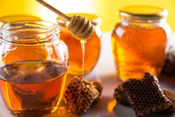Honey in jar with honey dipper on wooden background