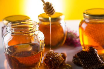 Honey in jar with honey dipper on wooden background