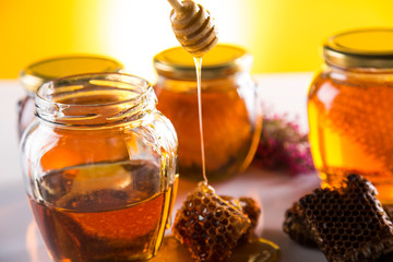 Honey in jar with honey dipper on wooden background