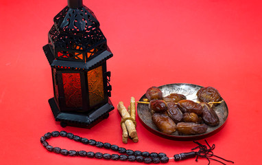Ramadan kareem concept with  dates and lanterns and rosary, siwak on red