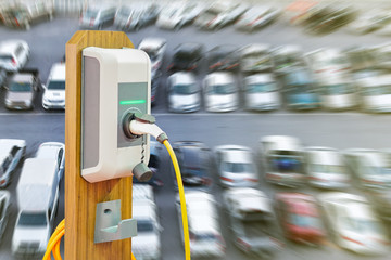 electric vehicle charging (Ev) station with plug of power cable supply for Ev car on many car blur background