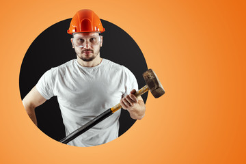 Bearded Man in a helmet holds a sledgehammer on an orange background. Concept of construction, contractor, repair.