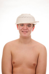 A young, fat, cheerful, smiling boy with a colander of pasta on his head. Plump body without clothing. White background. Portrait photo.