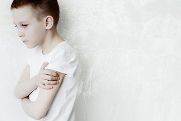 portrait of a very upset and offended child against a white wall. Family conflicts and parenting concept