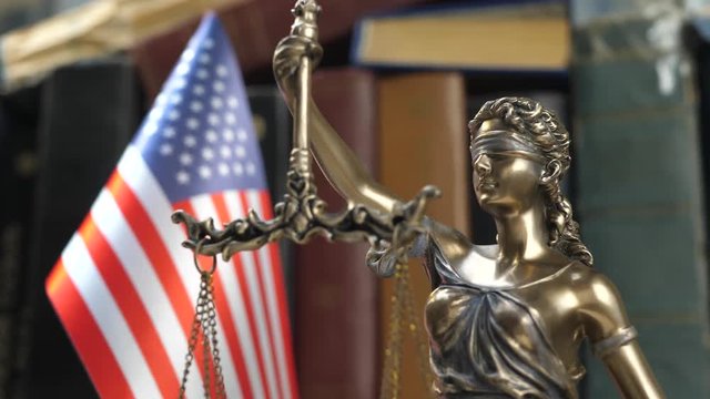 Statue of Lady Justice with Books and United States of America Flag. Tribunal and justice concept. Consultation with insurance lawyer and customer