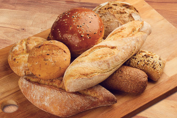 different types of bread on wooden kitchen cutting board