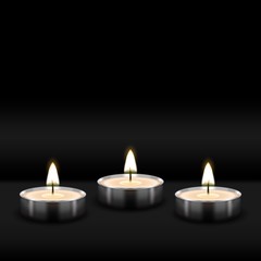Three tealight burning realistic candles on black background