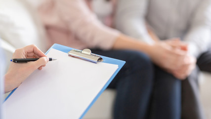 Psychotherapist writing in blank notepad at therapy session