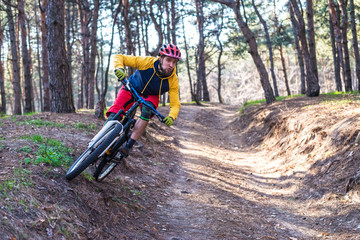 Fototapeta na wymiar Cycling, a cyclist in bright clothes riding a mountain bike on the edge of the slope. Active lifestyle.