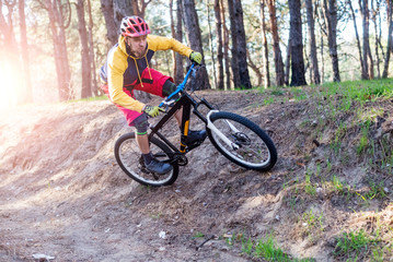 Cycling, a cyclist in bright clothes riding a mountain bike through the woods. Active lifestyle.