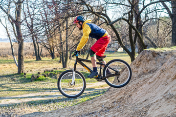 Cyclist in a bright sweater and red shorts riding a bicycle, downhill. Active lifestyle.