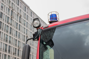 close-up picture of blue lights and sirens on a fire-truck on the background of a multistory building and the sky