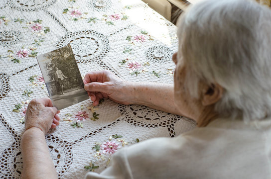 Older Woman Looking To The Photo With Young Herself. Old Photos, Nostalgie